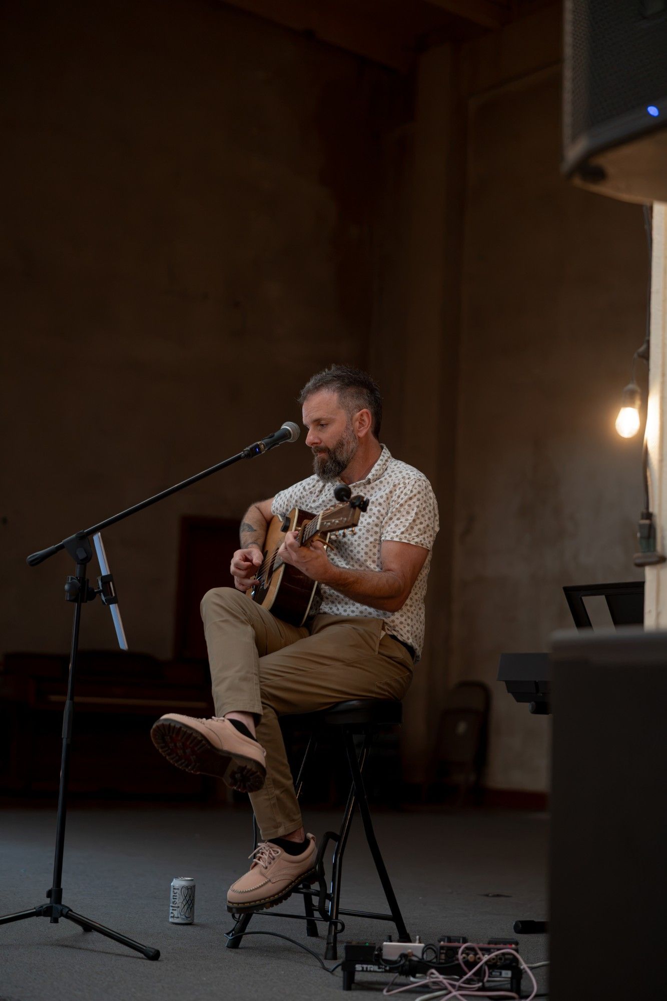 davyrockett singing and playing acoustic guitar on a stool